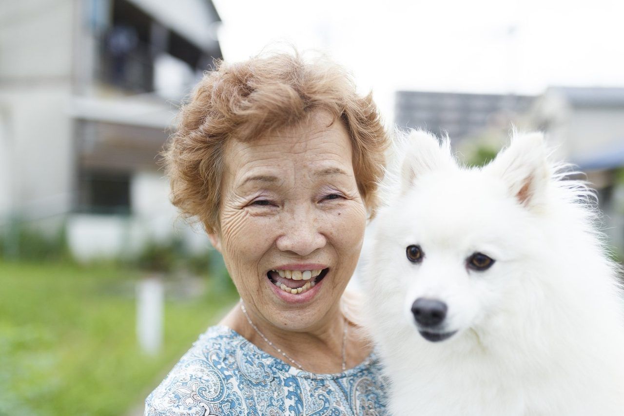 白い愛犬と一緒に、笑顔で寄り添うご高齢の女性