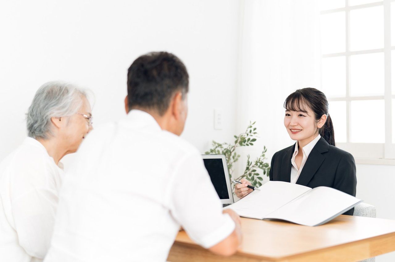 ご高齢のご夫婦と女性スタッフが、書類を前に話している場面