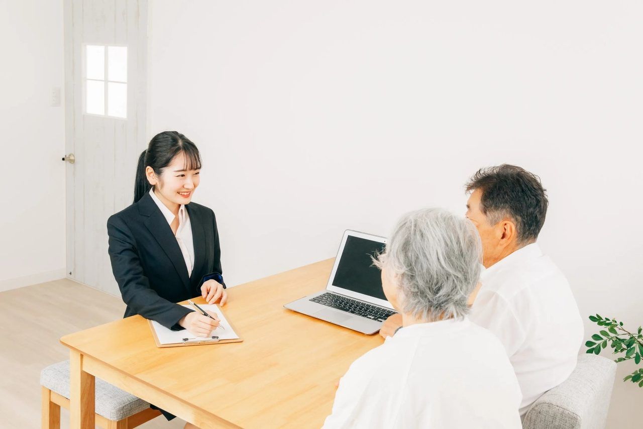 相談員が、ご高齢のご夫婦に書類を見せながら説明している場面