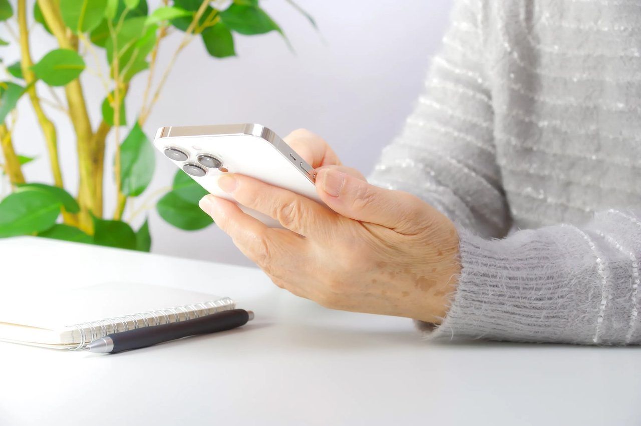 スマートフォンを手に持つ、ご高齢の方の手元