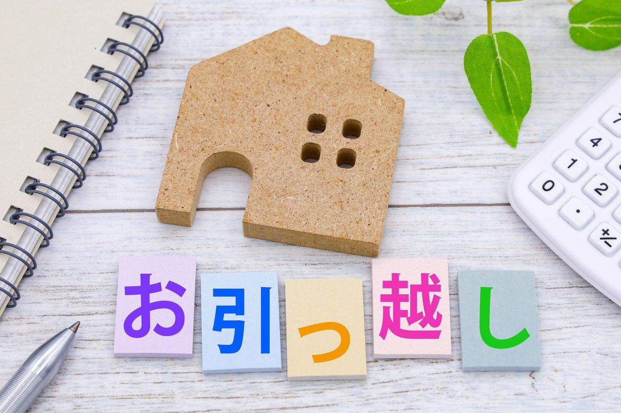 おうちの模型と「お引っ越し」と書かれた付箋、電卓