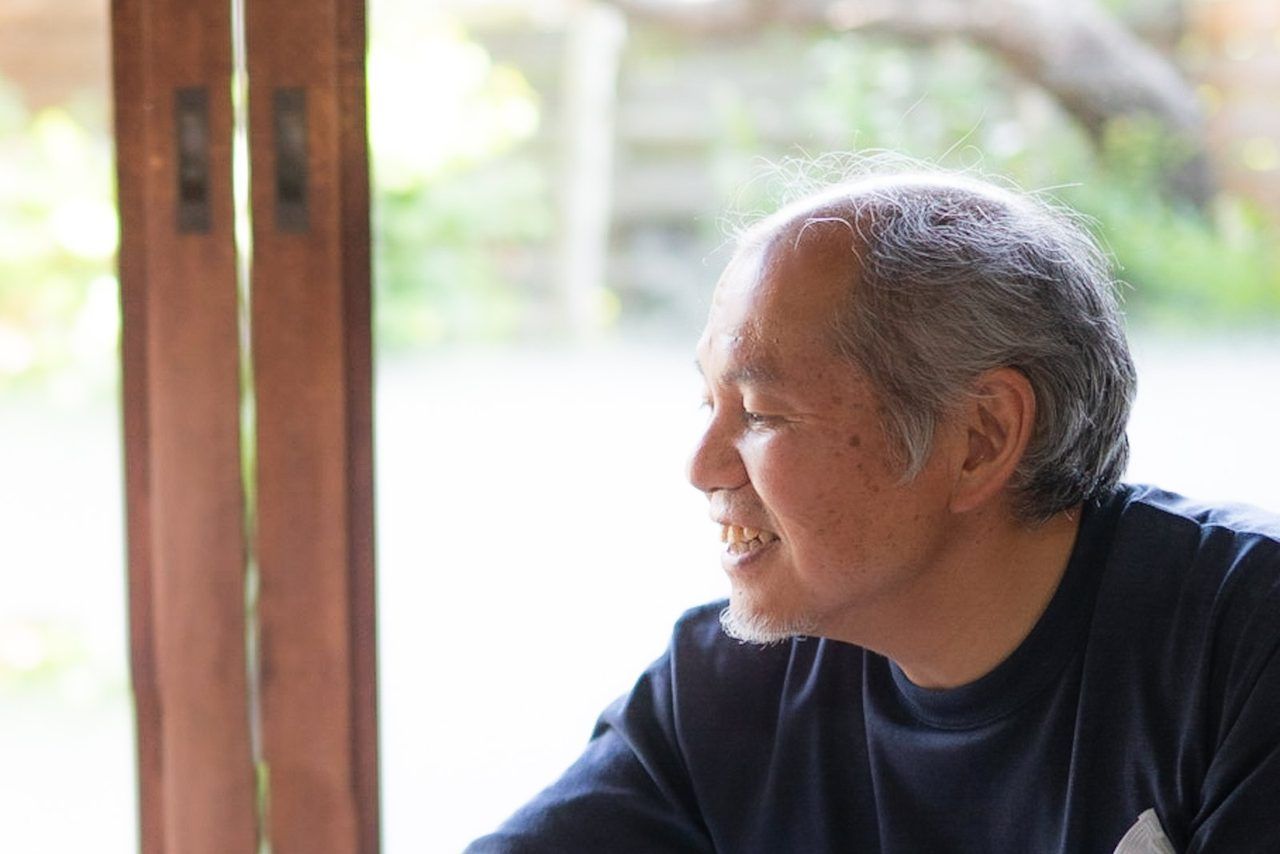 縁側で、穏やかに外を眺めるご高齢の男性(横顔)