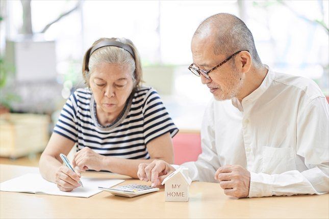 テーブルで書類を見ながら、書き込むご高齢のご夫婦