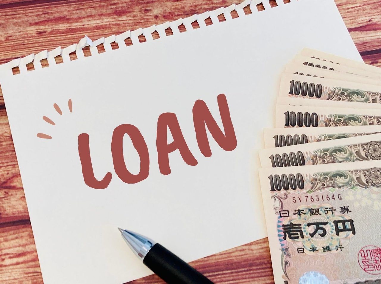 「LOAN」と書かれたメモと一万円札、ペン