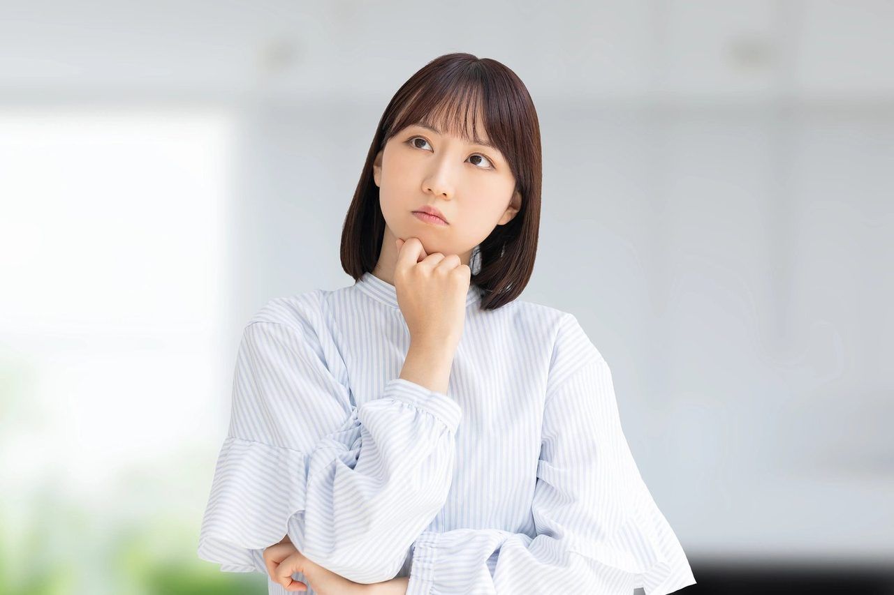 手をあごに当て、不安そうに考え込む女性