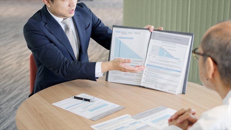 担当者が、資料を見せながら説明しているイ場面