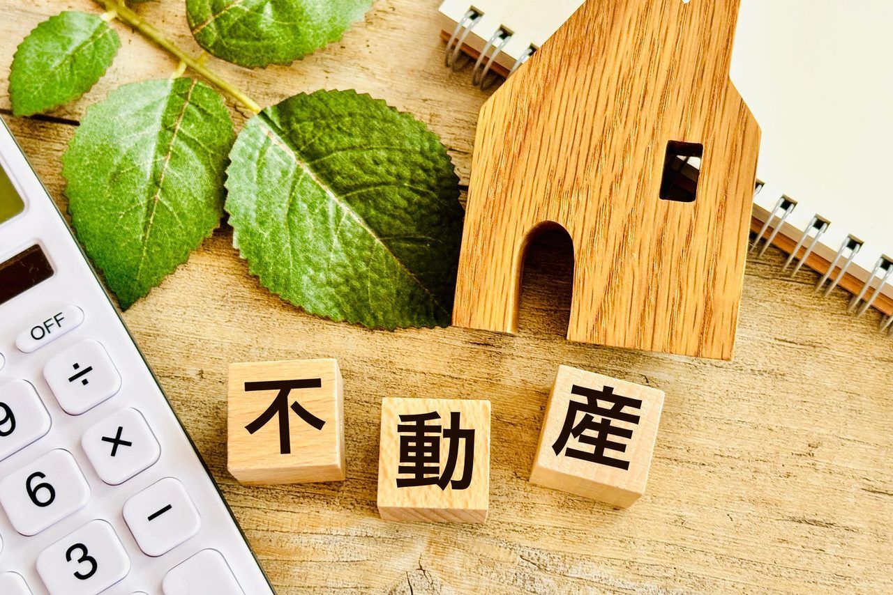 「不動産」の文字のブロックと、緑の木々