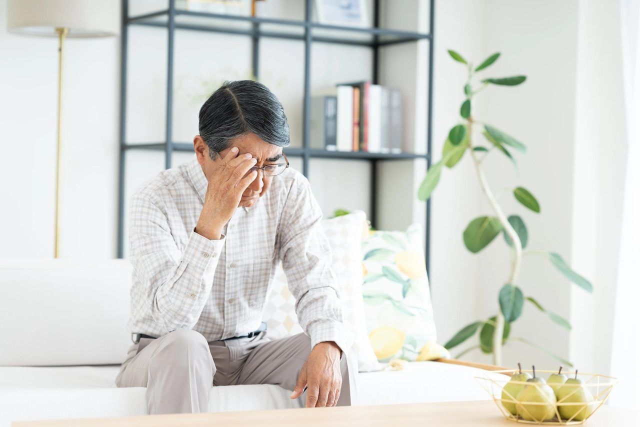 頭を抱えて、考え込むご高齢の男性