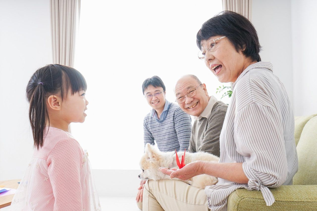 ご高齢のご夫婦とご家族が、リビングで談笑している場面