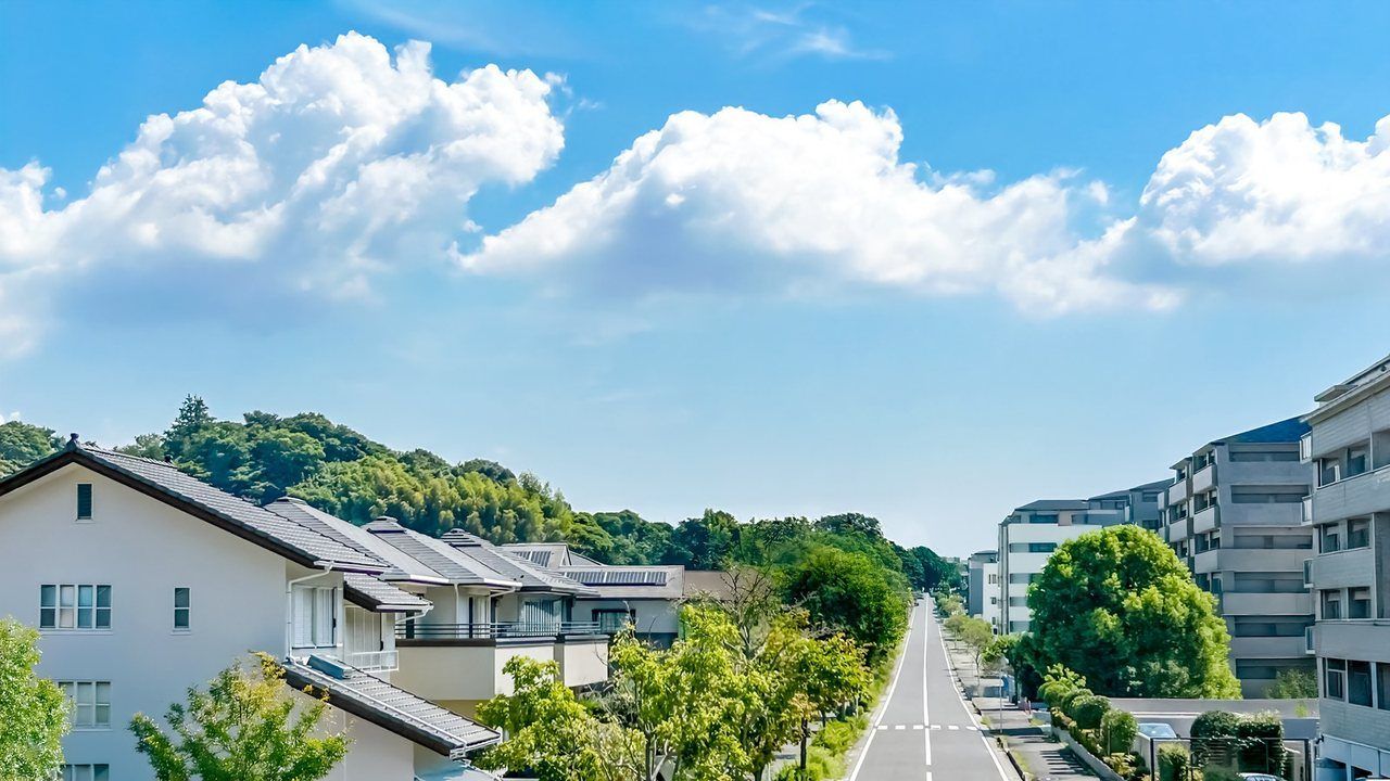 戸建て住宅とマンションが並ぶ、青空の下の街並み