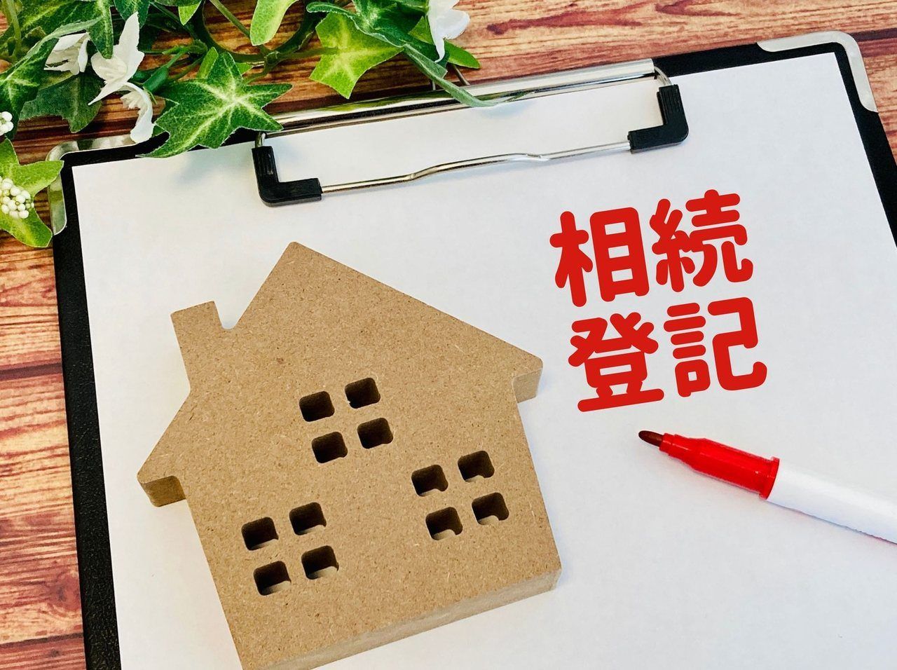 「相続登記」と書かれた家の置物とクリップボード