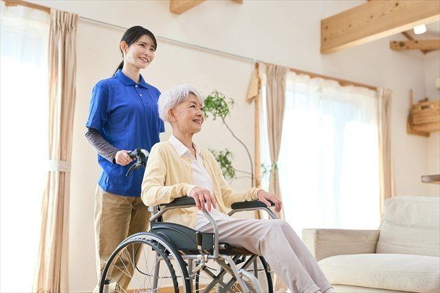 車いすの高齢の女性と、付き添うスタッフ