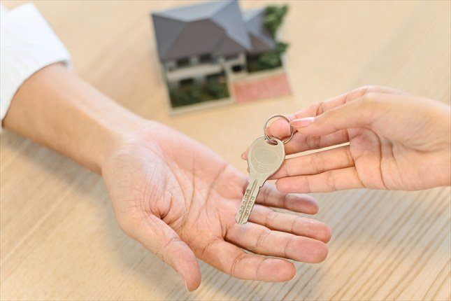 鍵を手渡す二人の手と家の模型